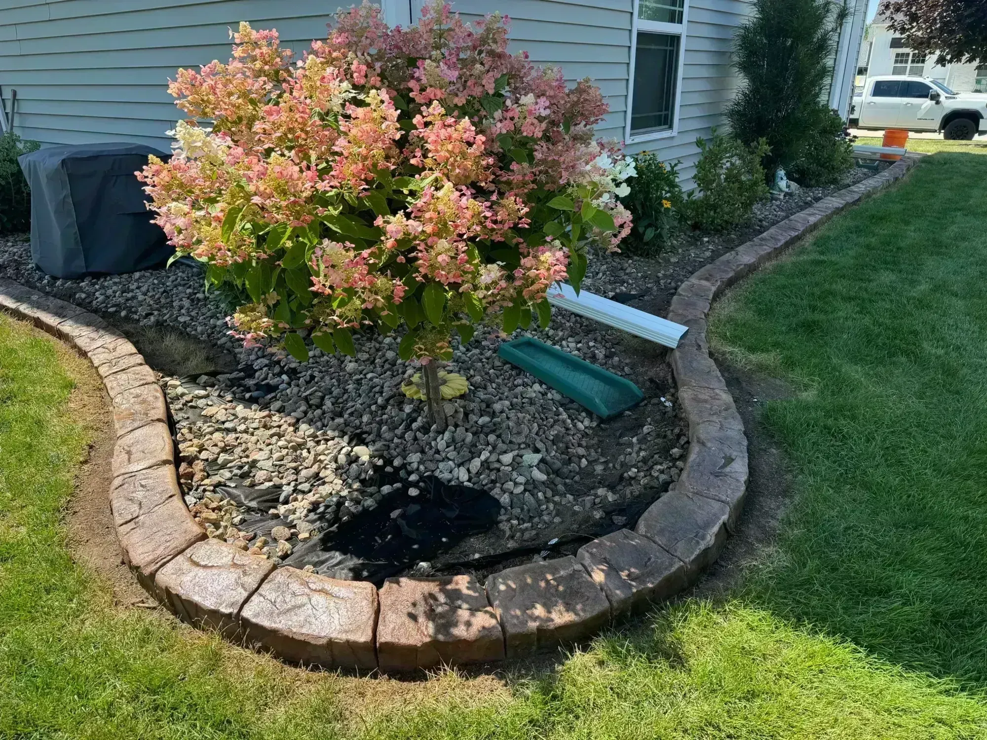 Straight concrete landscape curbing along garden bed